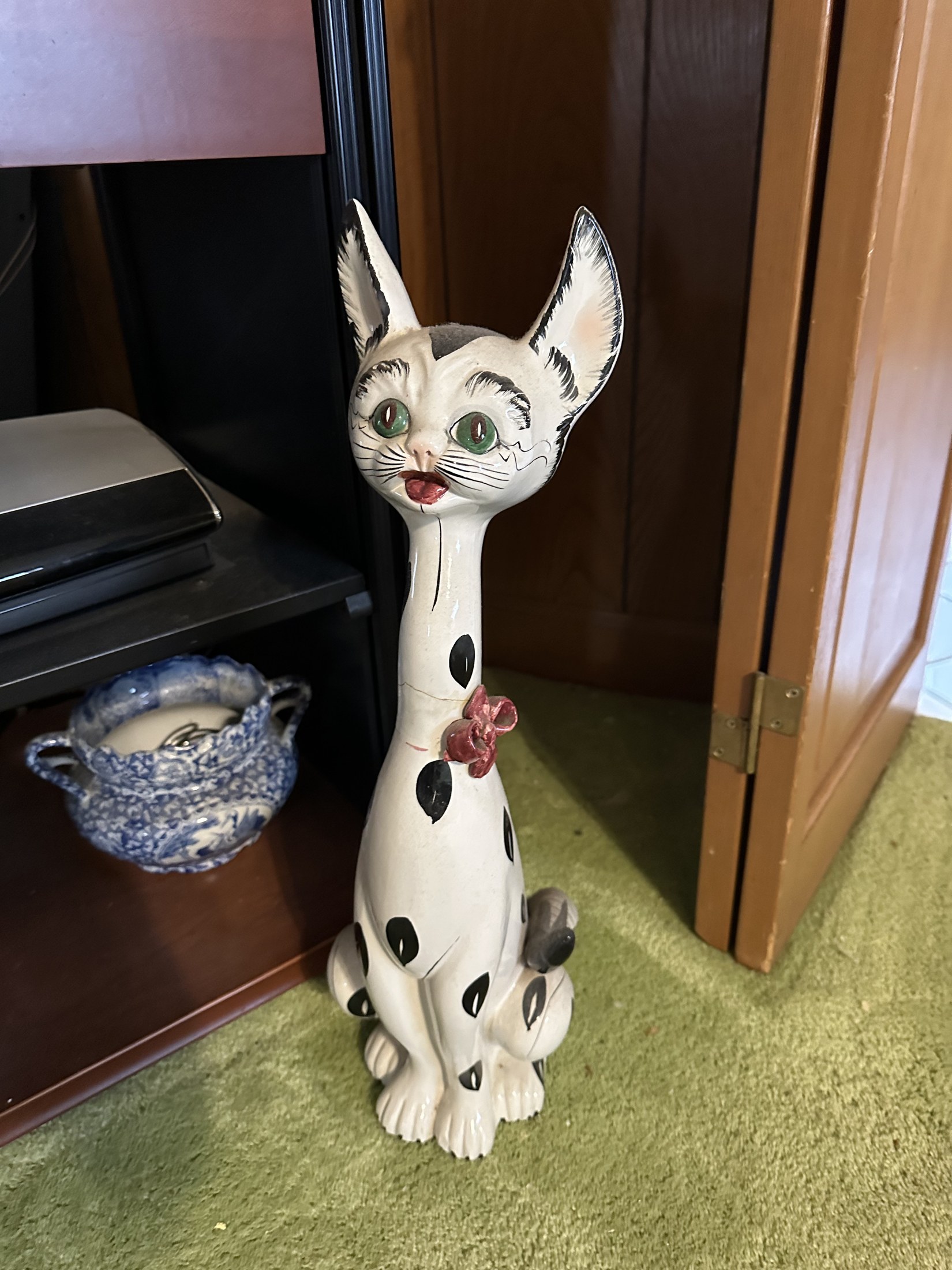 Tall vintage ceramic cat figurine with green eyes and a black polka-dot bow