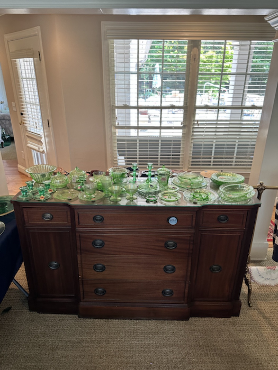 Green glassware arranged by color on antique furniture