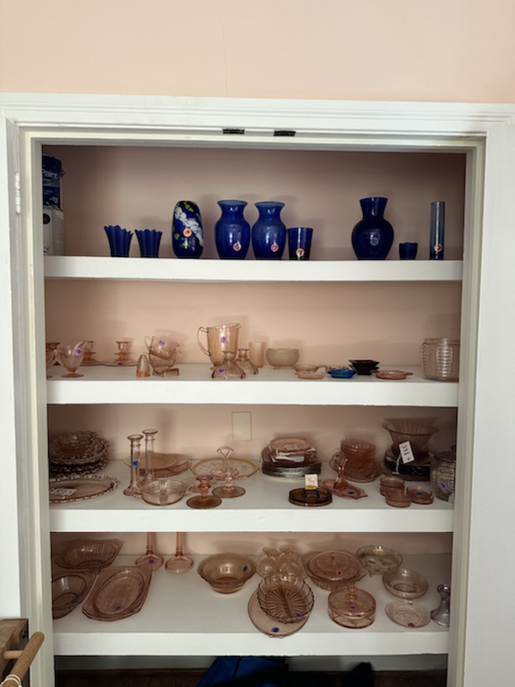 Pink glassware organized by form and tone on open shelving